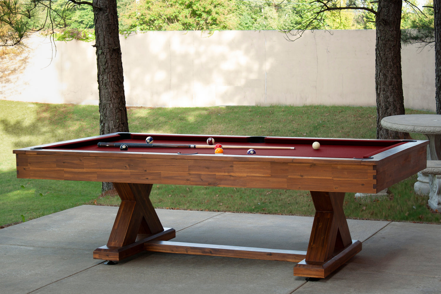 Legacy Billiards 8 Ft Cumberland Outdoor Pool Table in Natural Acacia Finish Outdoor Setting with Pool Balls and Cues on the Table